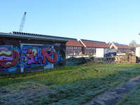 2023-35-206 Dichtgetimmerde en te slopen woningen in de Wielewaal. Op de achtergond verrijst de nieuwbouw aan de Rollostraat.
