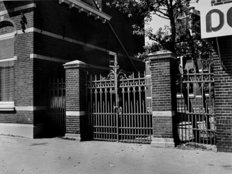 1976-640 Detail van de bewaarschool uit 1897 aan de westzijde van de Herenstraat. Smeedijzeren hek rechts van de voorgevel.