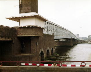 1981-1679 Gezicht vanaf de Maaskade op de Willemsbrug over de Nieuwe Maas, rechts de spoorbrug en aan de overzijde de ...
