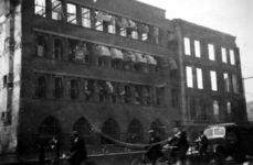 1983-765 Fietsers en voetgangers voor het verwoeste belastingkantoor aan de Boompjes na het bombardement van 14 mei 1940.