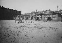 XXII-123-1 Een groepje kinderen speelt op de speelplaats achter de bewaarschool aan de Albregt Engelmanstraat.