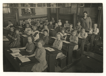 1975-380 Onderwijzeres M. van Loon met haar leerlingen in een klas van de school aan de Koepelstraat (?).