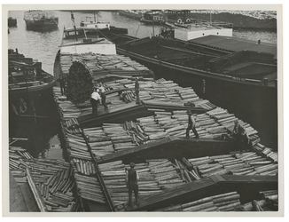 1976-4551 Met een takel lossen arbeiders een binnenvaartschip met hout.