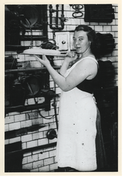 1977-3860 Een bakkersvrouw schuift deeg in de oven.