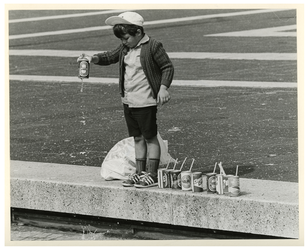 1982-2582 Een jongetje aan de rand van een bassin op het Schouwburgplein speelt met blikjes gevuld met water.