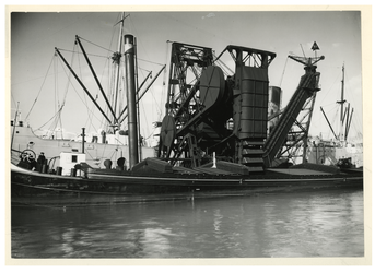 VII-559-00-01 Een kolentransporteur laadt of lost kolen van een binnenvaartschip.