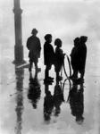 XXXIV-29-01-02-12 Kinderen in de regen bij de Zeevischmarkt. De jongen tweede van rechts heeft een hoepel in zijn hand.