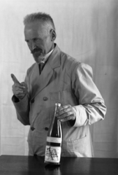 1976-11783 Man met fles azijn van Tromp & Rueb Azijnfabriek.Waarschijnlijk een reclamefoto.