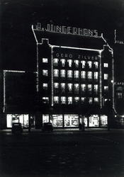 1976-11869 Avondopname van glas- en porceleinwarenhuis Jungerhans aan de Coolsingel.