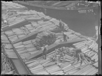1976-4552 Lossen van rollen hout van een schip in de haven.
