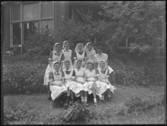1976-4764 Groepsfoto met verpleegsters in een tuin.
