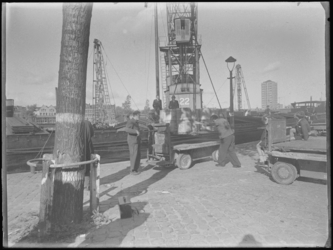 1976-4770 Het lossen van vaten uit een binnenvaartschip in de Coolhaven. Rechts op de achtergrond de GEB toren.