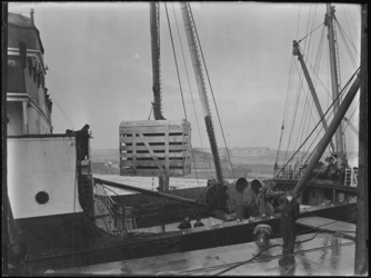 1976-5158 Laden en lossen. Het laden en lossen van kisten uit een schip aan de kade.