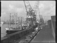 1976-5598 Schepen in de Merwehaven, aangemeerd langs de kade(n), hijskranen bij het goederenemplacement.