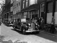 1976-6404 Voorhaven met geparkeerde auto's en mensen bij woonhuizen op het trottoir.