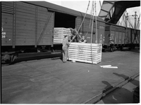 1976-7837 Overslag in de haven. Het laden / lossen van houten kisten in een treinwagon aan de kade.