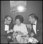 10614 Mrs. Evelyn Ritchey, public relations-manager van Hilton-Benelux-hotels, bekijkt samen met twee heren in smoking, ...