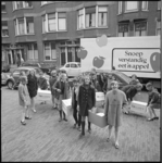 10673 Schooljeugd sjouwt met dozen; op de achtergrond een vrachtwagen met de slogan 'Snoep verstandig eet 'n appel'.