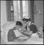 10975-2 Verpleegkundige helpt een bewoner met drinken uit een kopje terwijl hij in bed zit.