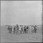 11039 Groep deelnemers aan de Wandel Zesdaagse; op het strand van Hoek van Holland met een schip op de achtergrond.