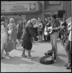 11535 Op het Binnenwegplein ter hoogte van de firma Jungerhans werpt een mevrouw iets in de gitaarkist van een spelende ...