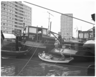 11937 In een roeiboot naast afgemeerde binnenvaartschepen zitten jongens te vissen in het Boerengat.