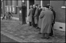 1898 8 oudere mannen staan in de rij voor een postkantoor; links een drietal postzegelautomaten; in het midden een ...