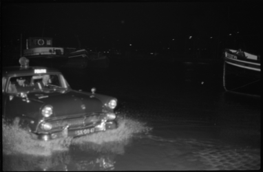 1939 Een donkerblauwe surveillance-auto van de politie rijdt - water tot aan zijn assen- over een ondergelopen kade.