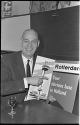 20034-42 Portret van A.J.M. (Tim) Schutter, directeur van de VVV Rotterdam; hij promoot met een poster zijn stad.