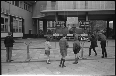 20893-1-8 Kinderen kijken naar een modeshow in de openlucht van de Rotterdamse herenmodeketen Gebr. Coster voor het ...