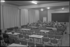 21617-4-1 Een zaal met mensen en enige ongebruikte tafels en stoelen tijdens de oprichtingsvergadering van het 'Comité ...
