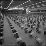 22401-3-8 Groot overzicht in Ahoy'-complex (Zuiderpark) met studenten aan tafeltjes tijdens examens.
