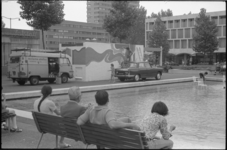 23737-6-10 Mensen op een bankje kijken naar het beschilderen van een dienstgebouwtje op het Schouwburgplein.