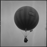 23842-2-6 Een gasballon (PH-BVH) met de tekst 'Nimbus' op het canvas hangt naast de NEH-Woudestein-nieuwbouw in de lucht.