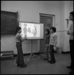 23985-2-8 Kinderen gastarbeiders krijgen taalonderwijs met gebruik van geprojecteerde foto's.