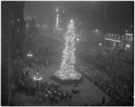 304-1 Vanuit een hogere etage van het stadhuis een overzicht van de met lampjes verlichte Noorse kerstboom met publiek.