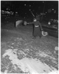 318-1 In verband met de gladheid wordt door politieagent in de avond zand op de rijweg gestrooid.