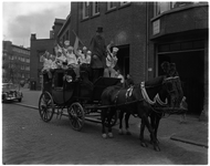 3246 Leerlingen van de Vakschool voor Bakkerij-en Hotelpersoneel zwaaien in de Rauwenhoffstraat vanaf een koets met paarden.