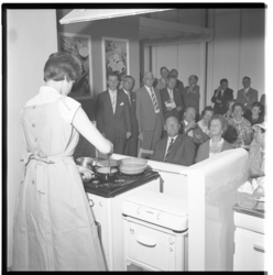 3310-1 Dame demonstreert kookvaardigheden tijdens de opening van een zuivelkeuken in het Bouwcentrum aan het Weena.