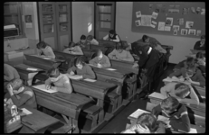 3970 Schriftelijk verkeersexamen in klaslokaal met schoolbanken van de Eloudschool, begeleid door hoofdagent J.D. Douma.