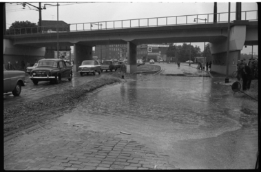 4316 Auto's rijden door grote plassen onder het spoorviaduct aan de Schiekade.
