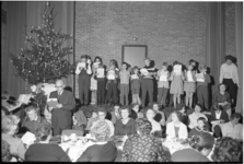 4761-1 Jongeren staan op een podium tijdens kerstmaaltijd voor zeemansgezinnen in de Pauluskerk.