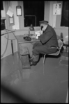 4832-2 Portier L. Bergsen van Swarttouw tijdens telefoongesprek in kamer met natte vloer.
