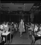 5112-2 Mannequin wandelt in de aula tussen de aanwezigen tijdens modeshow voor tieners van warenhuis 'De Bijenkorf'.
