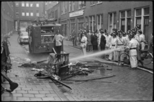 5271 In de Wolstraat worden resten van een verbrande zolderruimte geblust door brandweerman.