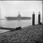 5933 Tussen het talud van een pier en hoge meerpalen vaart het USS vliegdekschip 'Essex' midden in de Nieuwe Waterweg.