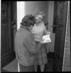 6895 Twee dames bestuderen bij twee openstaande huisdeuren een observatierapport van de 'Actie voor een Schoon Rotterdam'.