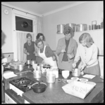 7144 Mejuffrouw C.W. de Werd (draagt wit schort) geeft in keukenruimte kookadviezen aan aanstaande huisvrouwen.