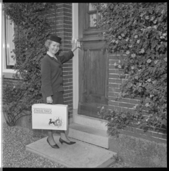 7390-2 Mejuffrouw A.H. Boutelje, hostess van de Felicitatiedienst Nederland, op huisbezoek.