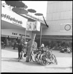 7405-3 Man tracht opgerold vloerkleed op zijn fiets te binden na een bezoek aan de opruiming in warenhuis Ter Meulen ...